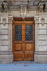Wooden Entrance Door Of A Classic Barcelona Building, Adorned With Stone Carvings. Historic Spanish...