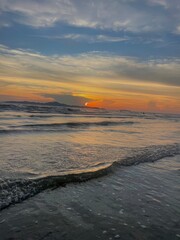 A beautiful evening sunset casts a golden reflection over the tranquil sea and sandy beach