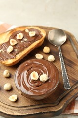 Toasts with tasty chocolate spread and hazelnuts on light table, closeup