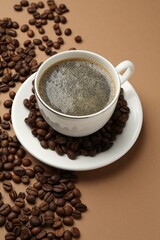 Aromatic coffee in cup and beans on beige background, above view