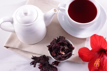 Tasty hibiscus tea, dry roselle sepals and beautiful flower on white table