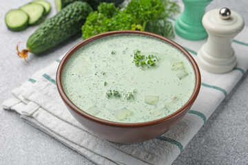 Tasty cucumber soup and ingredients on light grey table, closeup