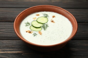 Tasty cucumber soup with dill and walnuts on wooden table, closeup
