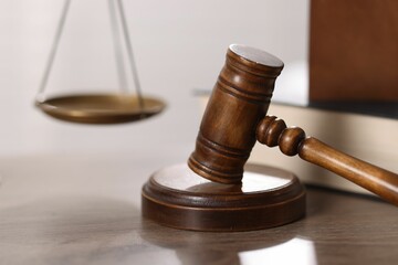 Judge. Gavel and scales on wooden table in office, closeup
