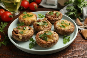 Tasty stuffed mushrooms and ingredients on wooden table, closeup