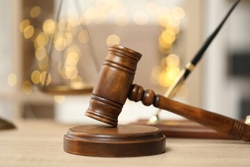 Judge's gavel on wooden table in office, closeup. Bokeh effect