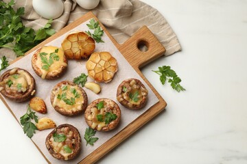 Delicious stuffed mushrooms with melted cheese, garlic and parsley on white table, flat lay