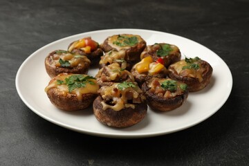 Tasty stuffed mushrooms on black table, closeup