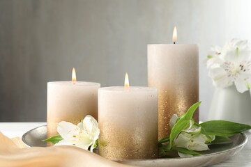 Burning candles and beautiful flowers on white table. Space for text