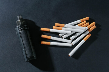 Electronic smoking device and cigarettes on dark table, flat lay