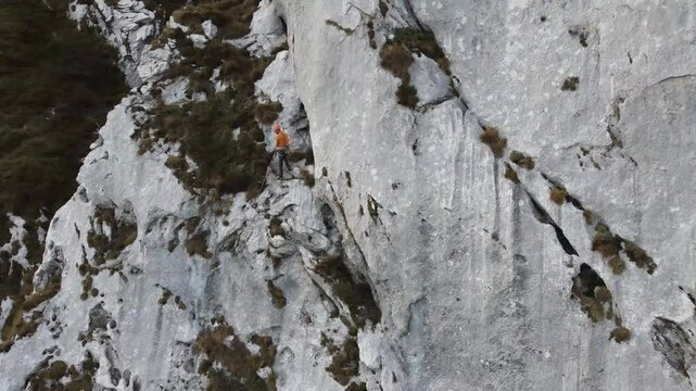 Climber ascending rock wall in scenic outdoor mountain landscape