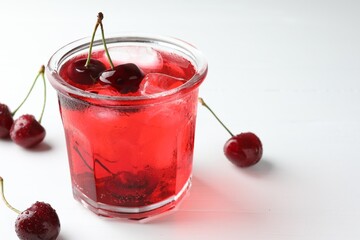 Tasty cherry soda with ice cubes and berries on white wooden table, closeup. Space for text