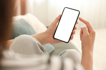 Woman using modern smartphone on sofa at home, closeup