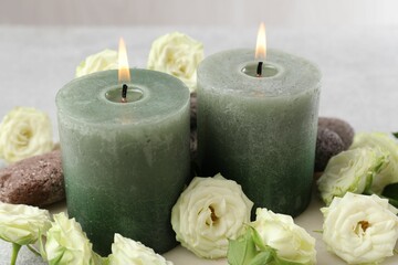 Burning candles, stones and rose flowers on table, closeup