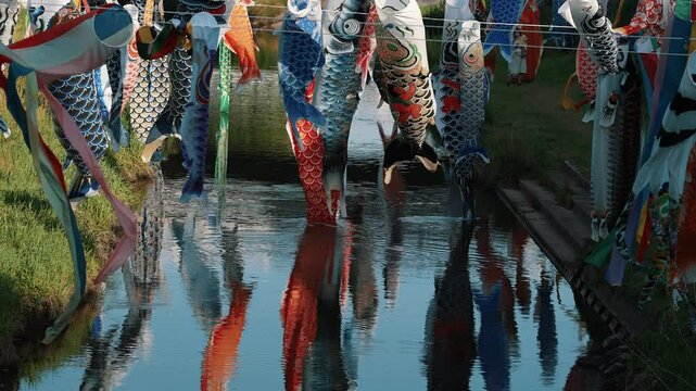 Colorful Koinobori carp streamers reflecting perfectly in still water.