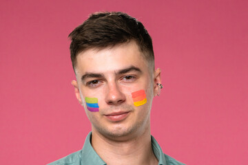 Young Individual with Rainbow Face Paint on Pink Background