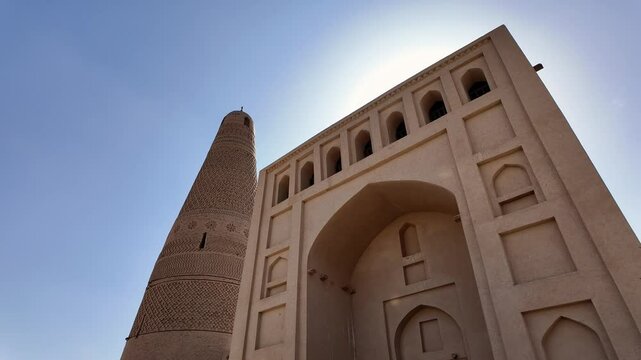 Turpan, China: Pan footage of the famous Emin Minaret next the the entrance of the Uyghur mosque that dates back from 1777 in the Turpan oasis in Xinjiang in China. Shot with front light sun. 