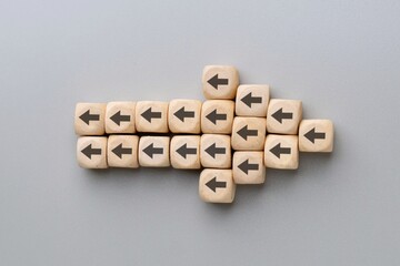 A large arrow formed by multiple wooden blocks with black arrows pointing in the opposite...