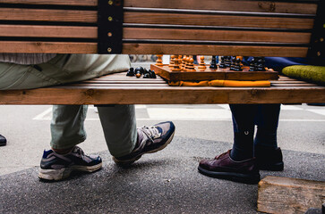 Salzburg in Austria. Two people sitting on a bench with a chess board in front of them. One of the people is wearing a pair of shoes