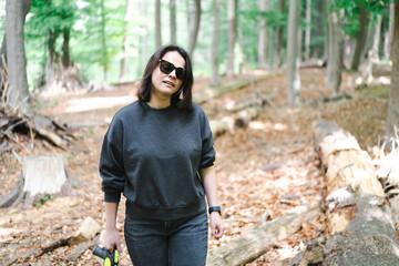 Stylish girl in forest setting with logs and foliage. Concept: calm strength, balance, personal...