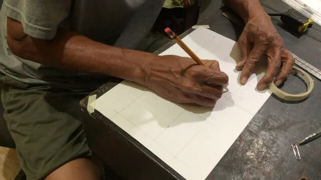 man is drafting a house plan using a pencil and T-square on a piece of bond paper at his desk. Timelapse