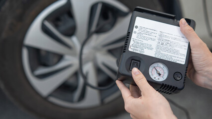 Woman holding a car tire pump. 