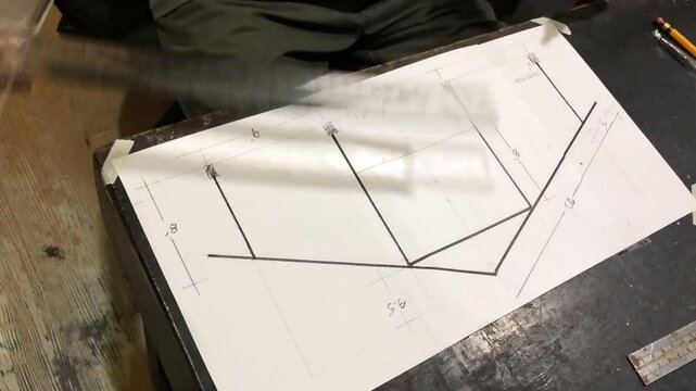 man is drafting a house plan using a pencil and T-square on a piece of bond paper at his desk. Timelapse