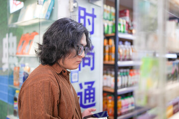 On a pleasant spring afternoon, a young Chinese man in his early twenties, wearing glasses, is seen buying cigarettes from a street vendor in the busy and stylish Huangpu District of Shanghai, China.