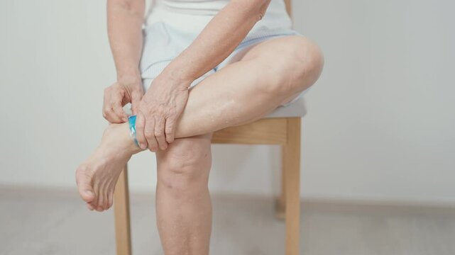 Elderly woman having leg pain with cold gel pack for Ankle Sprains or Achilles Tendonitis and Shin Splints ache. injury, hyperuricemia disease, Gout and Senior Health care