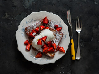 French toast with strawberries and cream ice cream on a dark background, top view