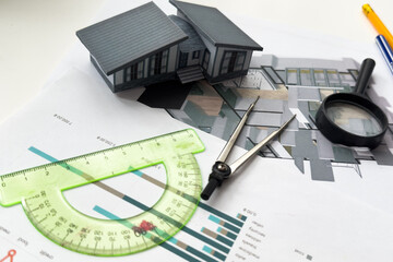 architectural model of houses on desk with drawing technical tools and blueprint rolls, isolated on...