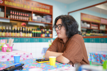 Two Chinese men in their early twenties, both wearing glasses, are casually waiting at a Thai...