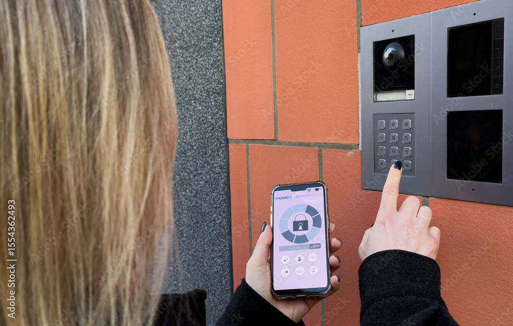 Poster young stylish woman getting access to the building by attaching smartphone to intercom. concept of m