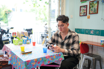 Two Chinese men in their early twenties, both wearing glasses, are casually waiting at a Thai...