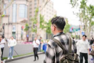 Two young Chinese men in their early twenties, both wearing glasses, walk side by side along the...