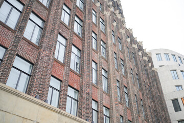 On May 31, 2025, a red brick building with colonial-style architecture stands along the Bund, where visitors and locals take photos and enjoy the warm afternoon sunlight in central Shanghai, China.