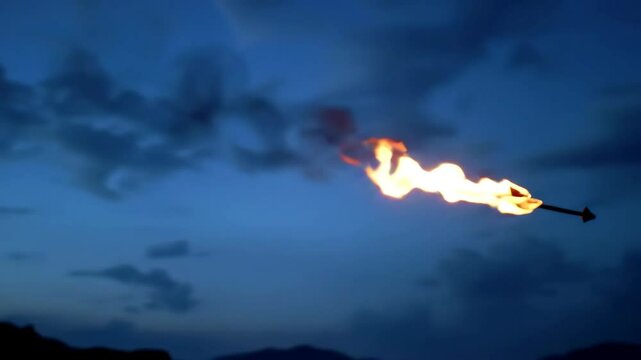 Epic slow motion tracking shot of a flaming arrow flying against a dramatic twilight sky