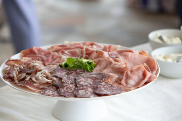 Delicious cold cuts platter with salami, mortadella and bacon decorating a table