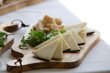 Manchego cheese slices with garnish on wooden serving board