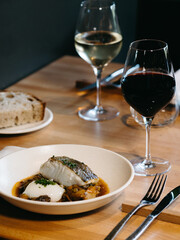 A set table in a restaurant with plates with fish and bread, and wine glasses