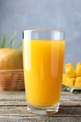 Tasty mango juice in glass and fresh fruits on wooden table, closeup