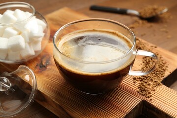 Tasty coffee in cup and sugar cubes on wooden table, closeup