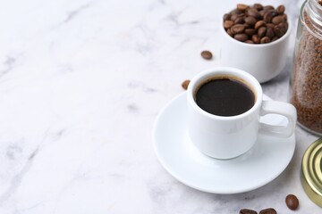 Aromatic hot drink, instant coffee and beans on white marble table, closeup. Space for text