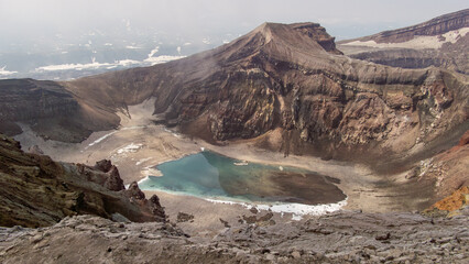 Majestic volcanic crater with turquoise lake surrounded by rugged terrain and steep cliffs,...