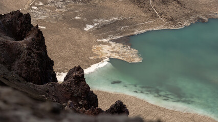 Aerial view of rocky terrain with turquoise water body surrounded by dry land, showcasing the...