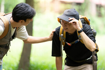 Father Supporting Son During Hike. A father comforting his son while taking a break in the woods.
