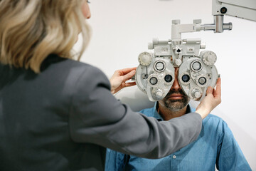 Optometrist conducting an eye examination with a phoropter in an optical clinic