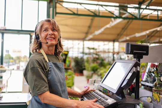 Smiling cashier with headset working at a garden center