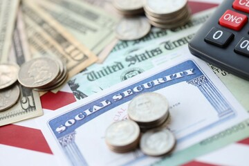 Fototapeta premium American US dollars money bills, social security number card and calculator on American flag