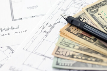 Big amount of US dollars money bills with pen and planning blueprints of residential building...